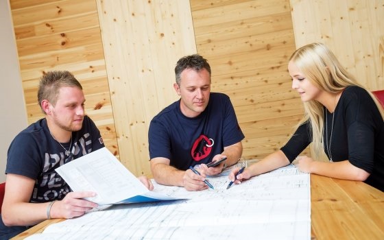 Ein Ausbildner mit zwei Zimmereitechnik-Lehrlingen bei der Planung und Zeichnung